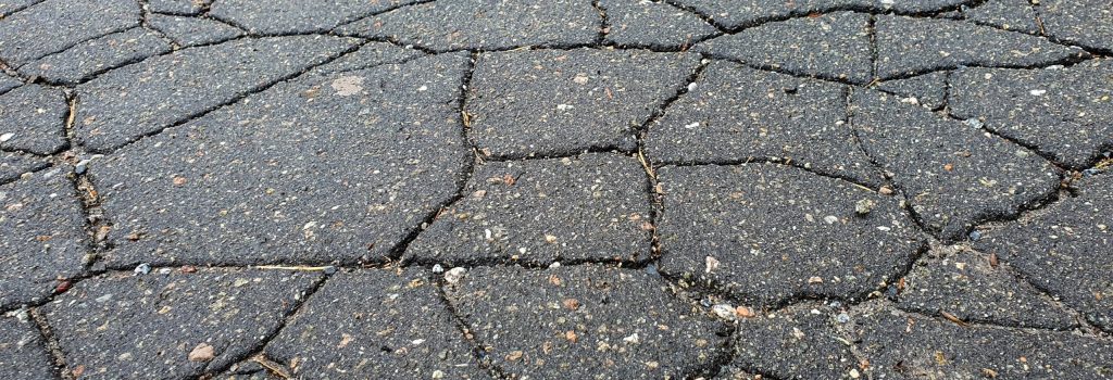 Severely cracked asphalt pavement showing alligator cracking and surface deterioration.